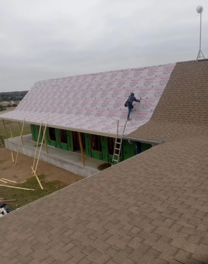 Worker preparing underlayment for a metal roof installation in Portland